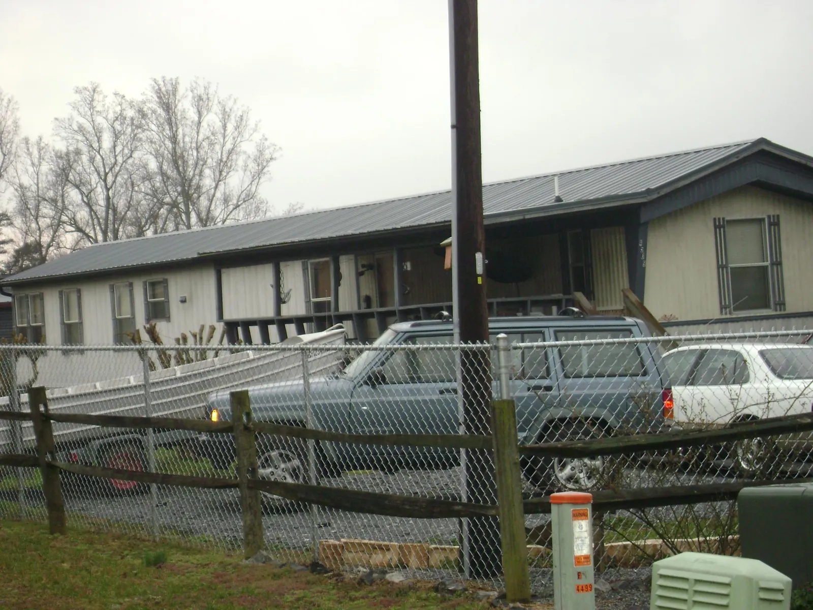 Dark metal roof on a long single story building behind a chain link fence in Red Cloud