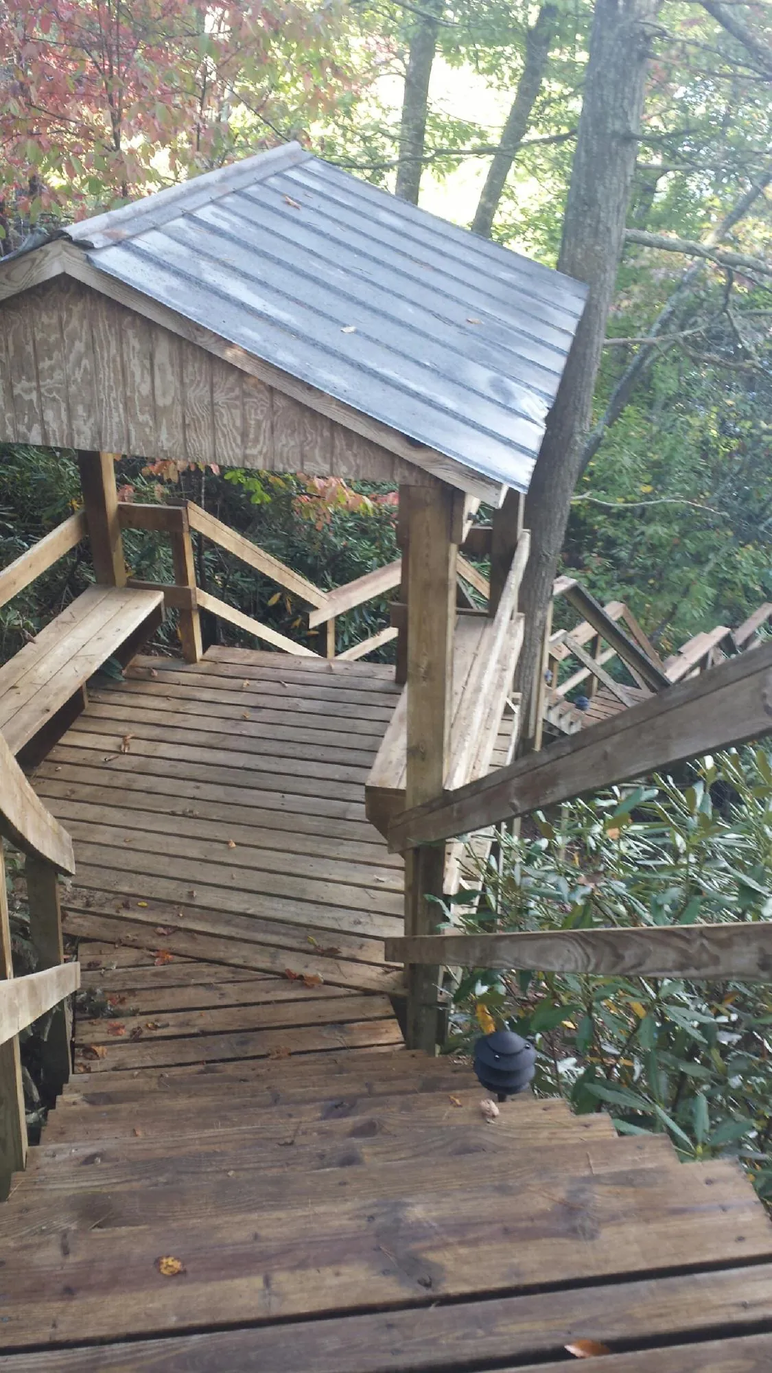 Metal roofed shelter over wooden steps on a wooded walkway — Skylight Repair & Installation work by our crew in Red Cloud