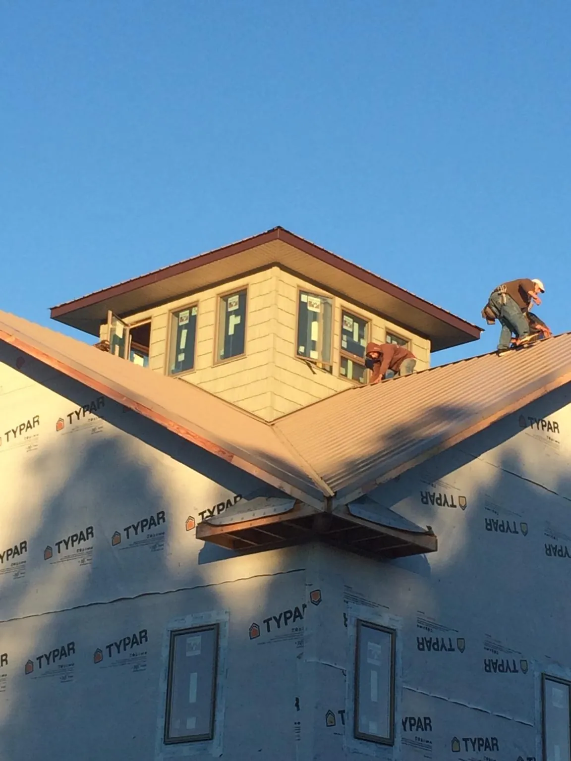 Roofers working around a rooftop cupola on a new metal roof at sunset — Roof Waterproofing in Red Cloud by Roofing Brothers